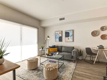 A living room with a grey couch, a glass coffee table, and a rug.